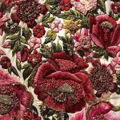 red flowers and green leaves are on a white fabric with pink trims in the center