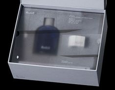 an open box containing two bottles of cologne on a black background, with the lid partially closed