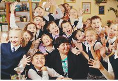 a large group of children and adults posing for a photo with their hands in the air