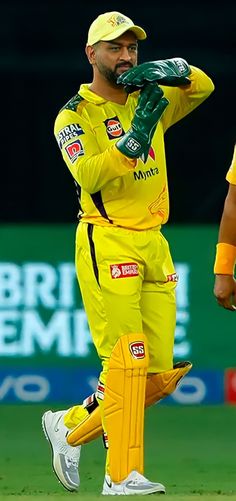 a man standing on top of a green field wearing a yellow uniform and holding a bat