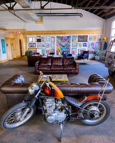 a motorcycle is parked in the middle of a room with couches and pictures on the walls