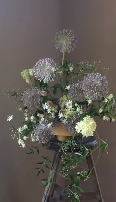 an arrangement of flowers sitting on top of a ladder