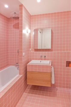 a bathroom with pink tiles on the walls and floor, along with a bathtub