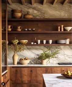 a kitchen with marble counter tops and wooden shelves