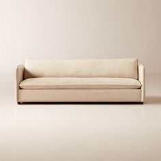 a white couch sitting on top of a floor next to a beige wall with a wooden frame