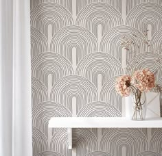 two vases with flowers on a shelf in front of a wallpapered background