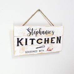 a wooden sign hanging from the side of a wall that says stephanie's kitchen seasoned with love