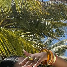 a woman is reaching up to pick something out of the palm tree with her hand