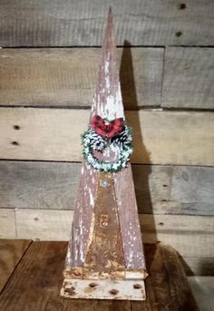 an old wooden christmas decoration on top of a piece of wood in front of a wall