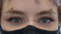 a close up of a person wearing a black mask with gold studs on their eyes