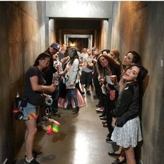 a group of people standing in a long hallway next to each other holding cups and drinks