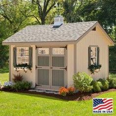 a small white shed sitting in the grass