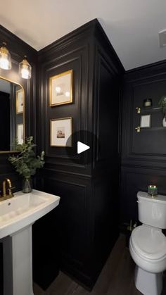 a white toilet sitting next to a sink under a mirror in a bathroom with black walls