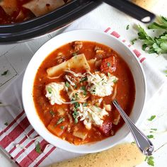 a bowl of soup with tortellini bread and garnish on the side