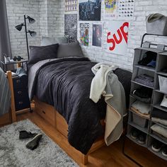 a bedroom with white brick walls and wooden flooring, black bedspread on the bed