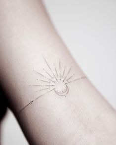 a small sun and moon tattoo on the left side of the arm, with lines drawn across it