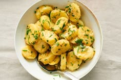 a white bowl filled with potatoes and garnished with parsley