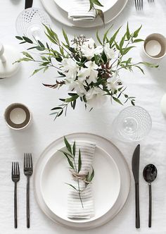 the table is set with black and white place settings, silverware, and flowers