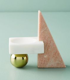 a marble object with a gold ball in front of it and a white piece on the other side