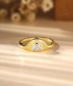 a yellow gold ring with a white diamond in the center on a table next to flowers