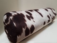 a roll of toilet paper covered in brown and white cow hide print on the wall