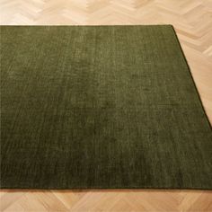 a green rug is on the floor in a room with wooden floors and parquets