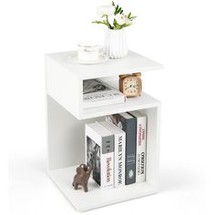 a small white book shelf with books and a clock on it's side table