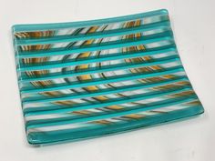 This fused glass Venetian blind style tray was made with alternating strips of patterned art glass and transparent turquoise glass. The strips were assembled in such a way as to give an optical illusion of a glass Venetian blind. Decorative as well as functional, this tray is food safe and will work well as a serving tray or a catch-all dish. This one-of-a-kind tray measures 8" by 6". Designed and handmade in my home studio. Thank you for taking the time to visit my shop! For more of my handmade Stained Glass Studio, Picture Necklace, Venetian Blinds, Glass Tray, Glass Artwork, Orange Art, Turquoise Glass