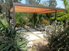 an outdoor covered patio area surrounded by trees and plants