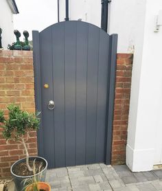 a blue door is open in front of a brick wall and potted planter