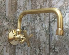 a gold faucet mounted to the side of a marble wall