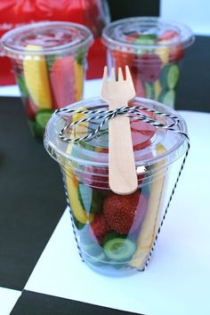 plastic cups filled with different types of fruits and veggies on a checkered table