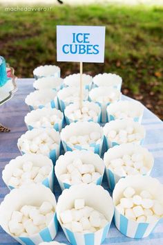 cupcakes are lined up on a blue tablecloth with ice cubes in them