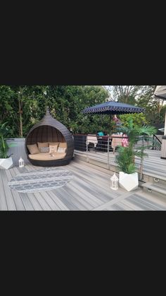 an outdoor living area with furniture and umbrellas on the deck, surrounded by greenery