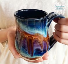 a person holding a coffee mug with an artistic design on the outside and inside it