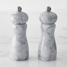 two marble salt and pepper shakers sitting on a counter top with one being turned to the side