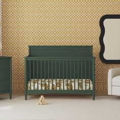 a green crib in front of a wall with a mirror and chair next to it