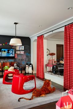 a tiger laying on the floor in a living room with red drapes and curtains