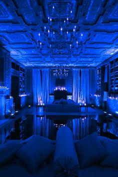 a living room filled with lots of furniture and blue lights on the ceiling above it