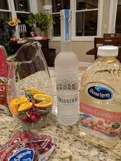 a bottle of white cranberry water next to some fruit on a counter top