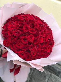 a bouquet of red roses is wrapped in white paper and ready to be held by someone