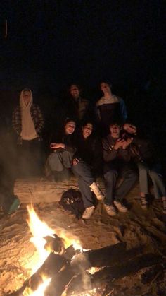 a group of people sitting around a campfire at night