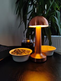 a table with a lamp, bowl and plate on it next to a laptop computer