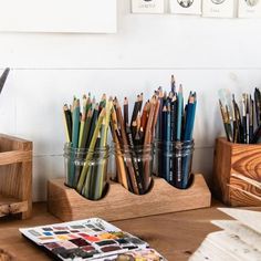 there are many different colored pencils in the cup on the desk next to each other