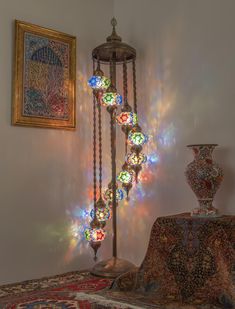 a lamp that is sitting on top of a bed next to a painting and vase