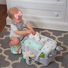 a baby sitting on the floor next to a diaper box with items in it