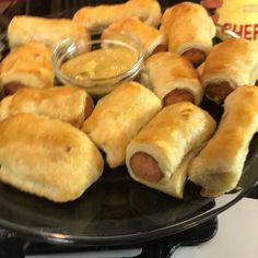 a plate full of pigs in a blanket with dipping sauce on the side for dipping