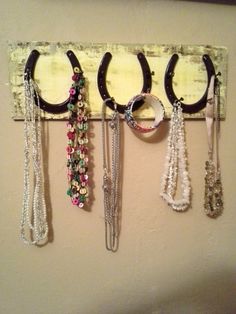 several pairs of black and white scissors hanging on a wall with beaded necklaces