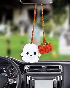 a car dashboard with a stuffed ghost hanging from the dash board