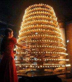 a woman standing in front of a lighted christmas tree with lights on it's sides